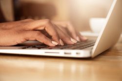 Hands typing on a laptop