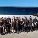 Performers posing in front a bus.