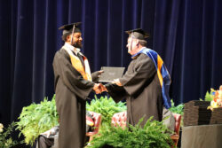 Male graduate receives diploma from Interim President Phillips